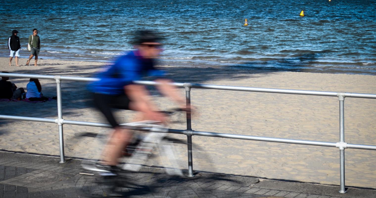 image showing a cyclist blurring passed the beach