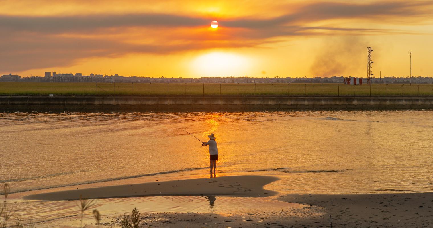 image of a person fishing at sunset