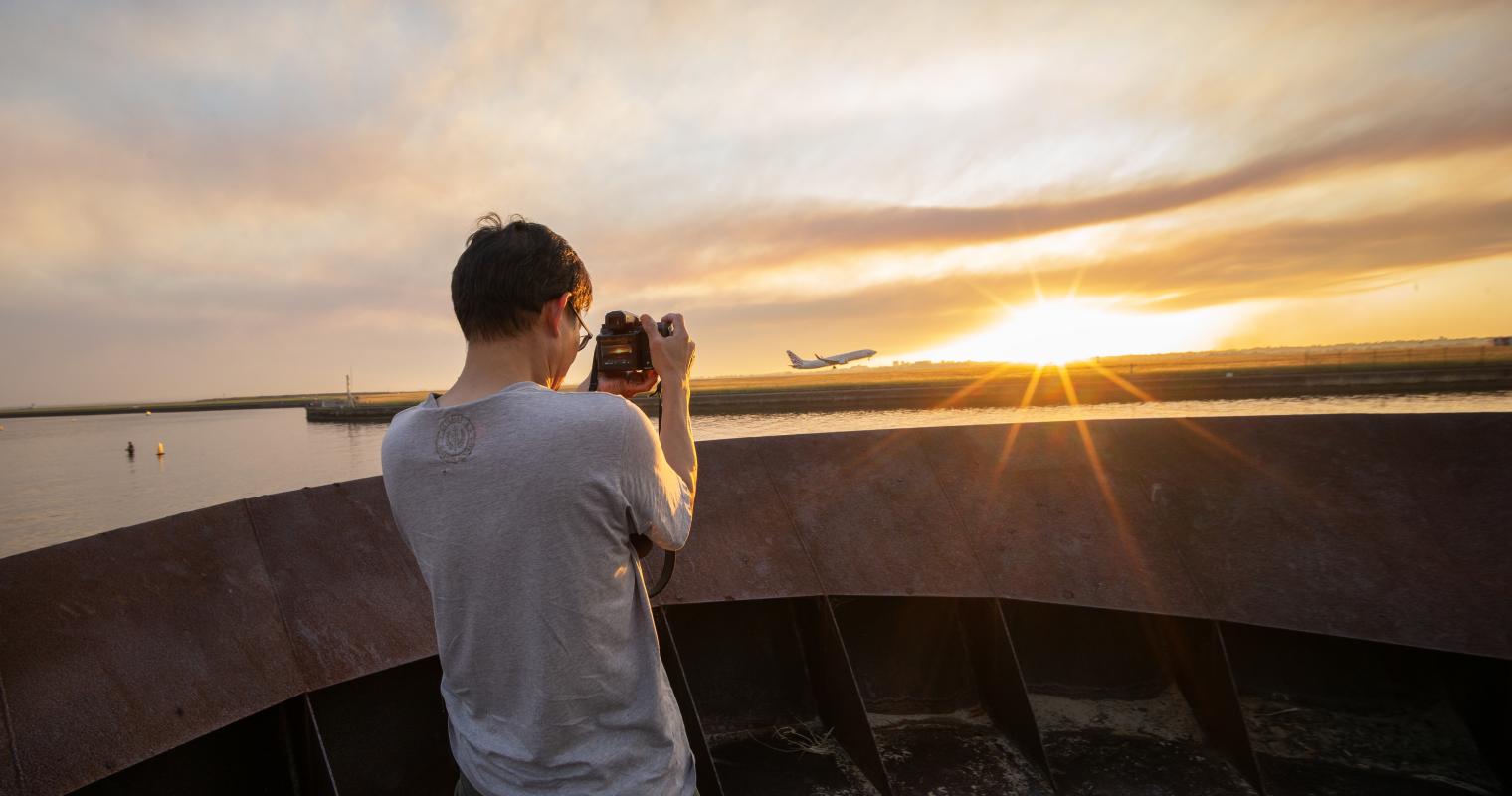 image of a person taking a photo of a plane taking off
